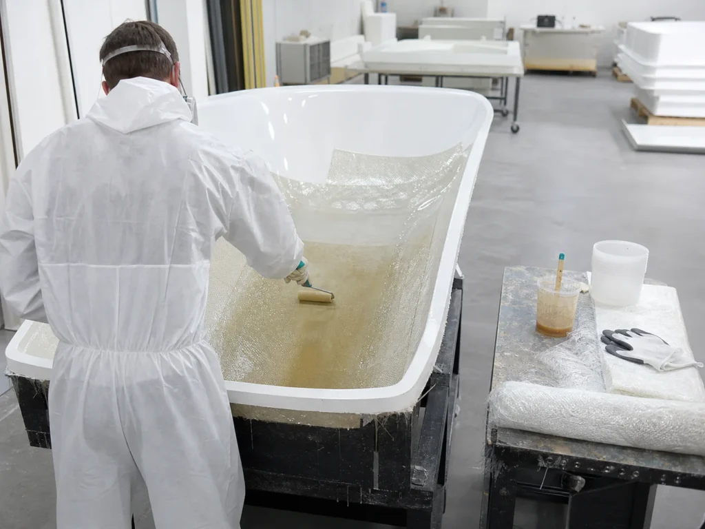 Technician applying glass fibre and resin backing to a sanitary ware shell